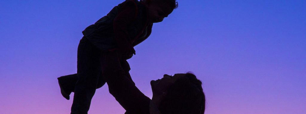 A woman holds a baby up in the air