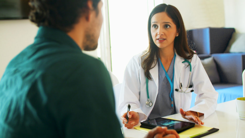 A physician speaks to a patient while using EHR