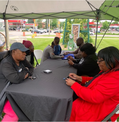 People meet across a table and under a tent