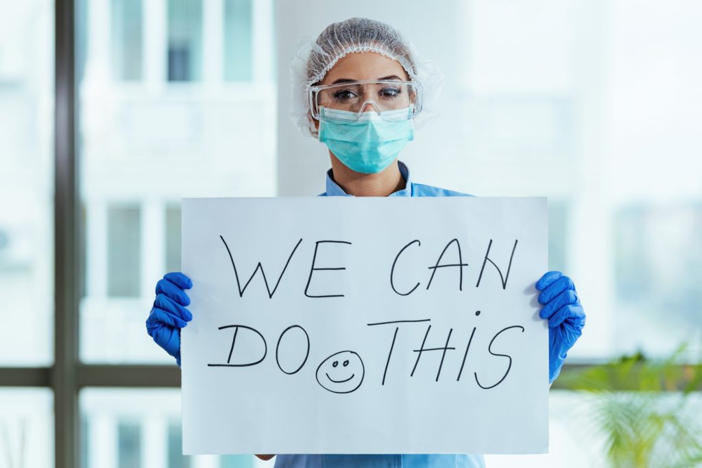 Doctor with a sign that reads, We can do this!