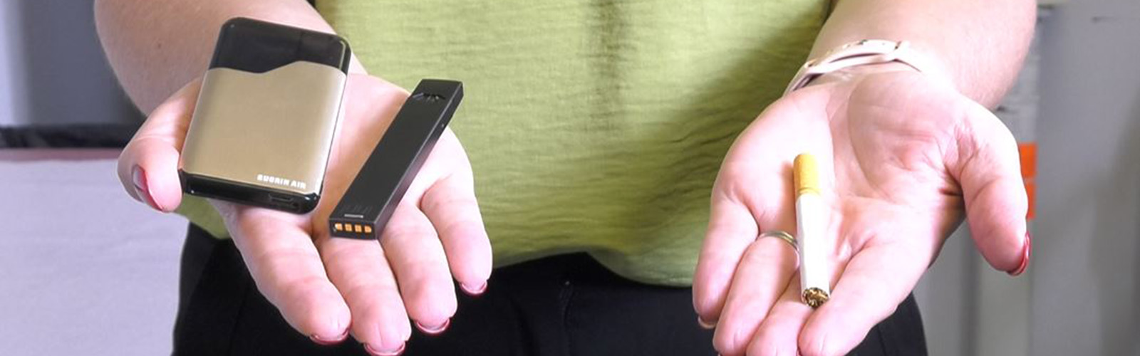 two hands, one holds vaping products and the other holds a cigarette